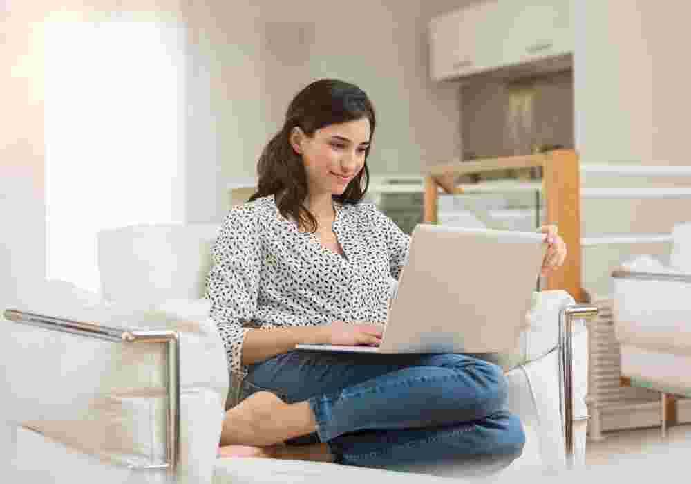Women looking at her laptop sat on white chair