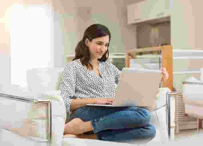 Women looking at her laptop sat on white chair